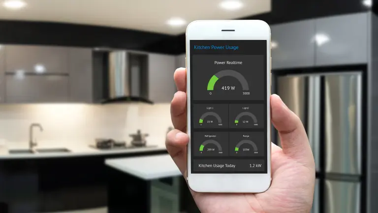 A hand holding a smartphone, blurry kitchen in the background