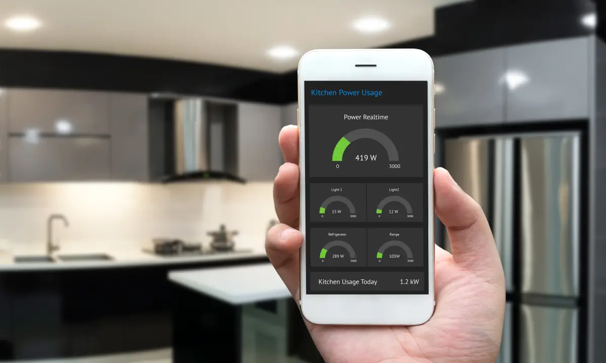 A hand holding a smartphone, blurry kitchen in the background